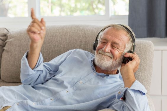 Senior retirement man listen to music using headphone feeling happy in his home
